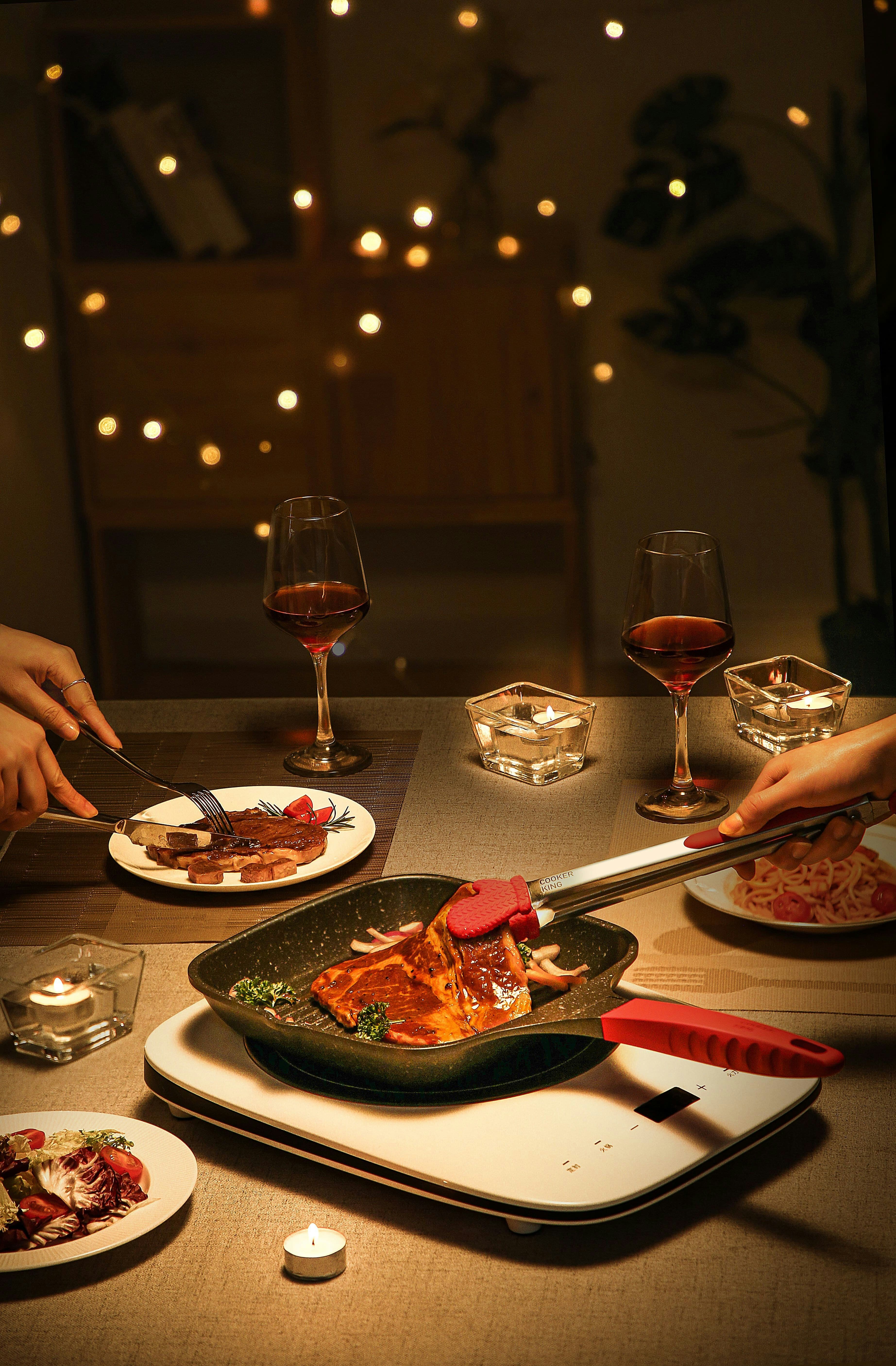 Hands plating the next course at a candlelit table
